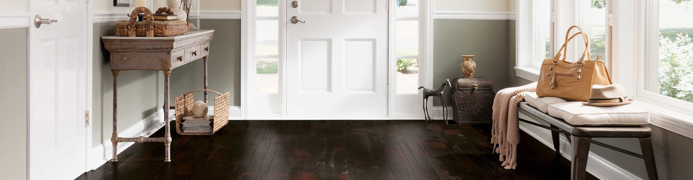 oak burgundy dark stain flooring in entry way of home with white door and chandelier lighting